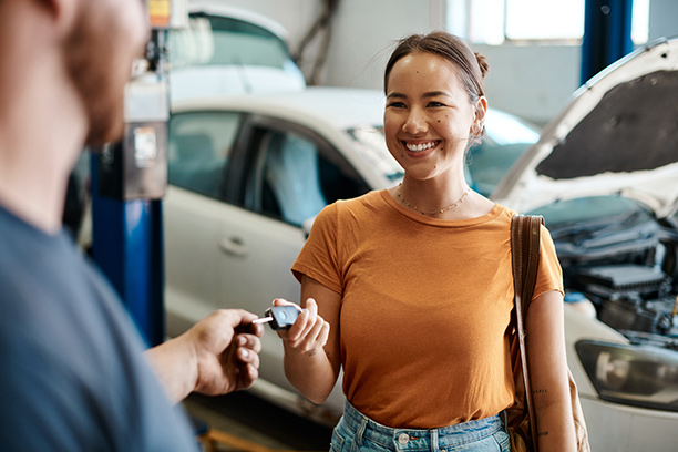 eisemans-garage-warranty-coverage Smiling woman handing car key to mechanic